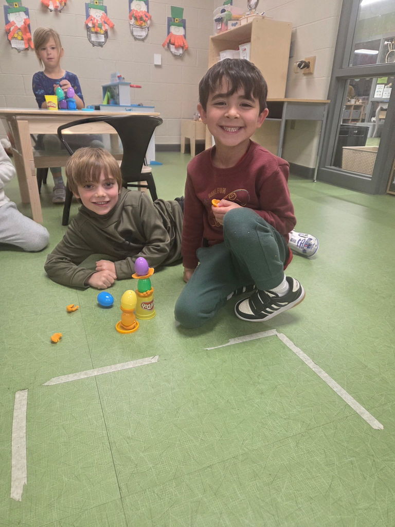 students playing with playdoh and stacking eggs in a classroom for a stem activity.