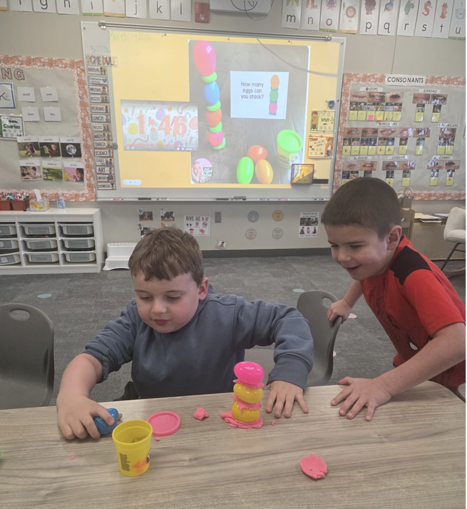 students playing with playdoh and stacking eggs in a classroom for a stem activity.