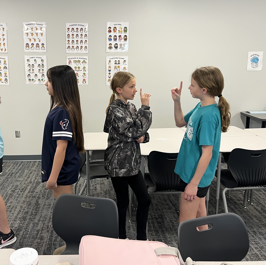 Three students practice signing with each other.