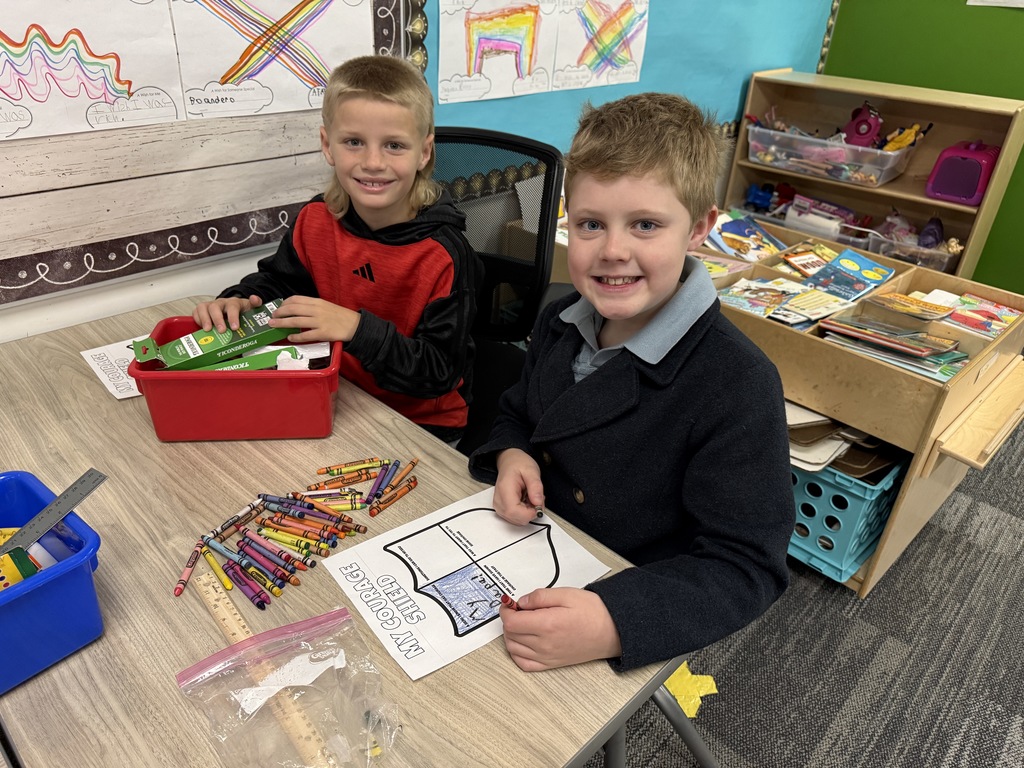 Two boys sit at a table working on their courage shield.