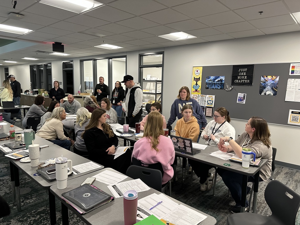 Groups of teachers sit and discuss at tables. 