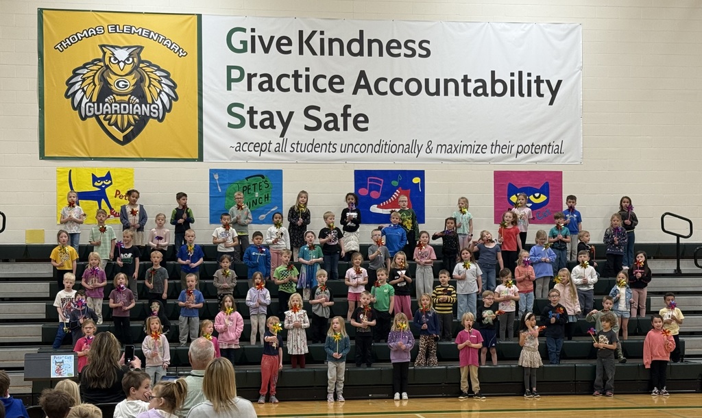 Kindergarteners practice for their music program standing on the bleachers