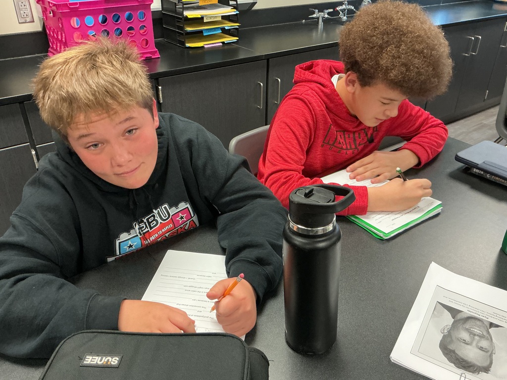 Photo of two male students sitting at a desk filling out a worksheet.