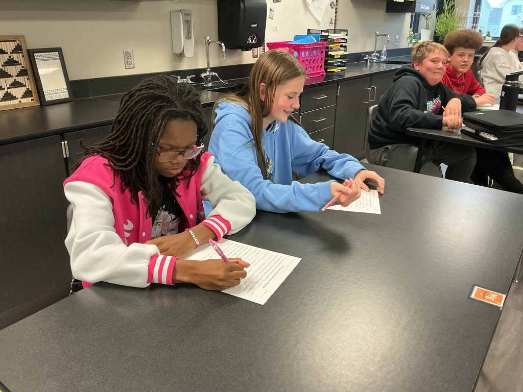 Photo of two femaile students sitting at a desk filling out a worksheet.