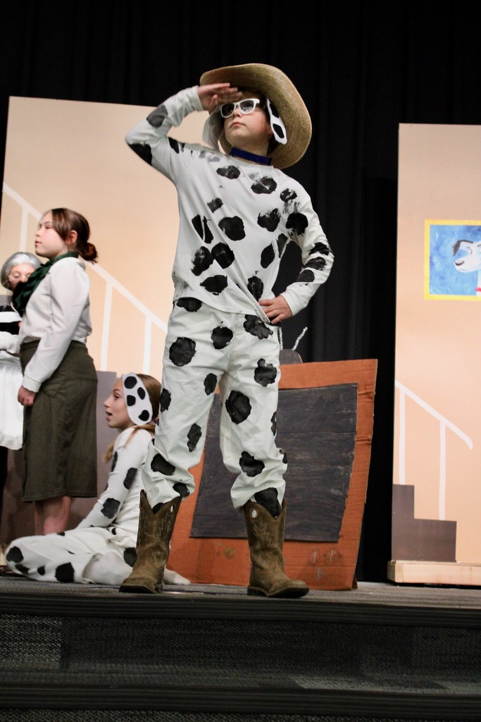 A student dressed as a dalmatian in a cowboy hat and boots saluting.