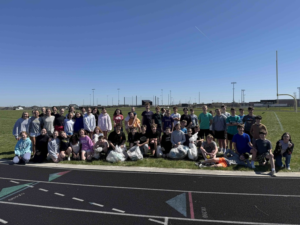 Photo of all AEP students lined up with all of the trash they cleaned up in bags in front of them.