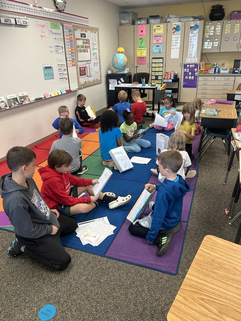 A group of students sitting down and reading their writing to each other.