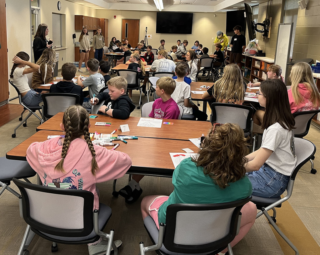 large conference room filled with students listening to instructions to begin math solutions