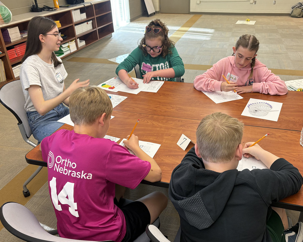 high school student guiding fifth graders with math games and solutions