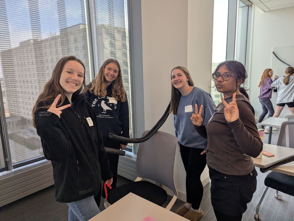 Photo of four female students standing and looking at the camera and smiling.