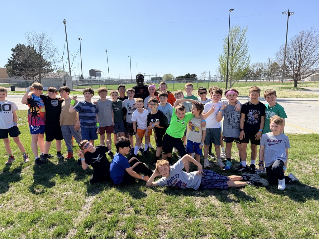 A similar group photo of the boys and their mentor posing on the grass, with some children making silly faces and poses.