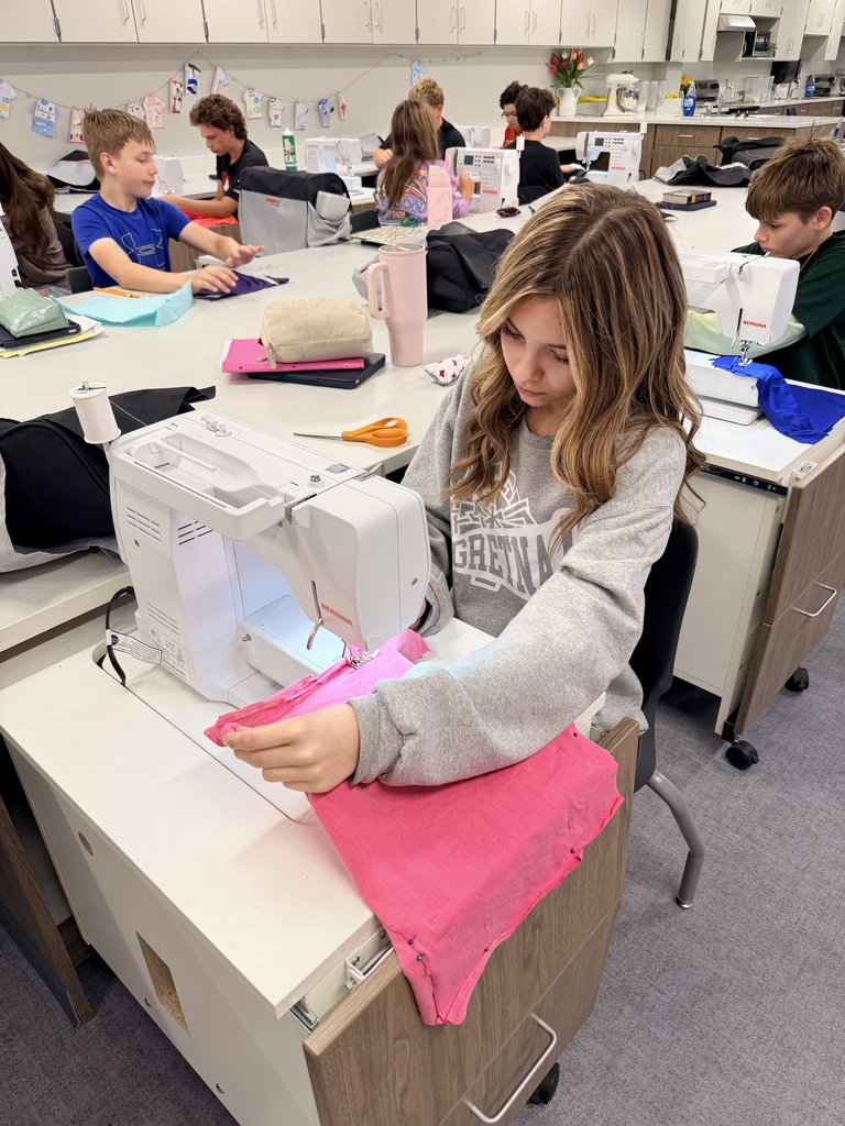 A female student sits at a sewing machine sewing. 