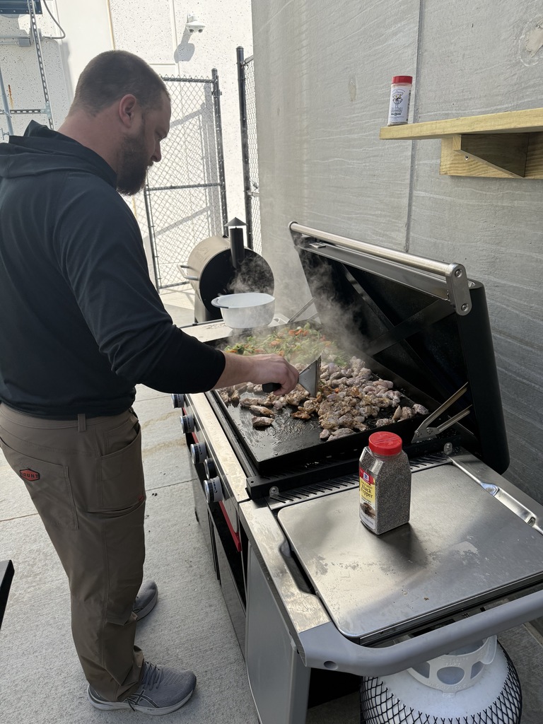 A man cooks at a grill. 