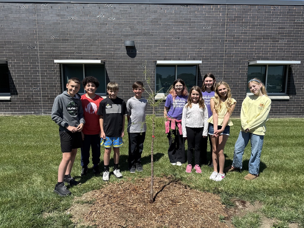 Four fifth grade boys are on the left and five fifth grade girls are on the right next to a tree they planted.