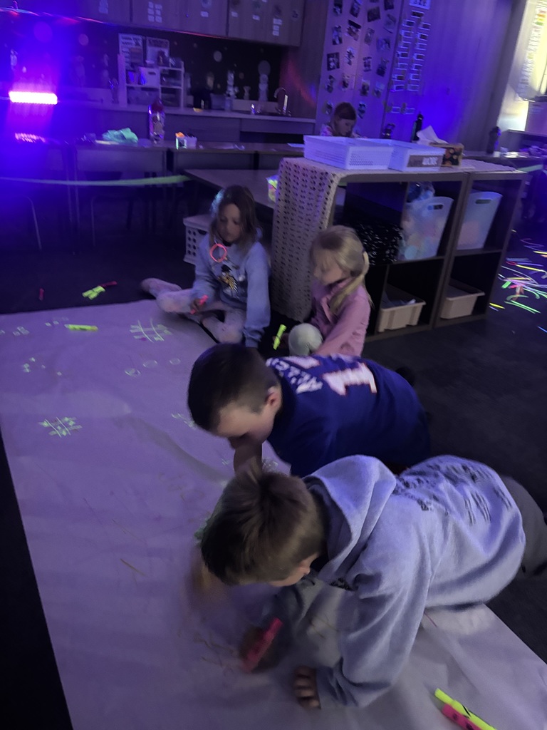 students coloring with highlighters under a blacklight