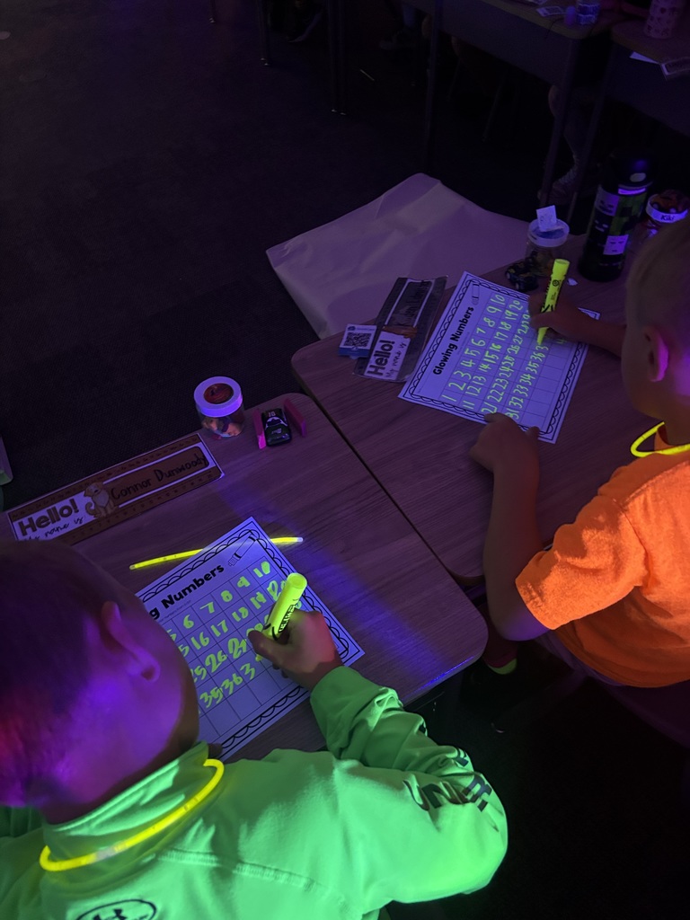 students writing with highlighters under a black light