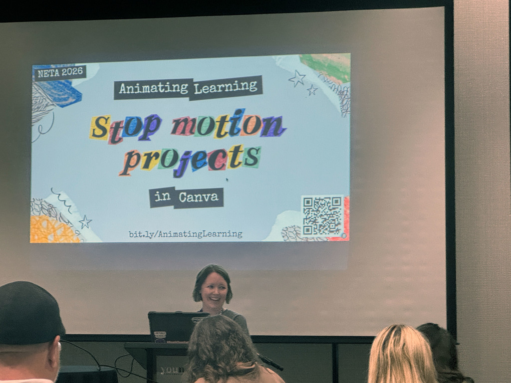 Erica Walsh smiling standing behind the podium with presentation screen behind her reading "Animated Learning Stop Motion Projects in Canva"