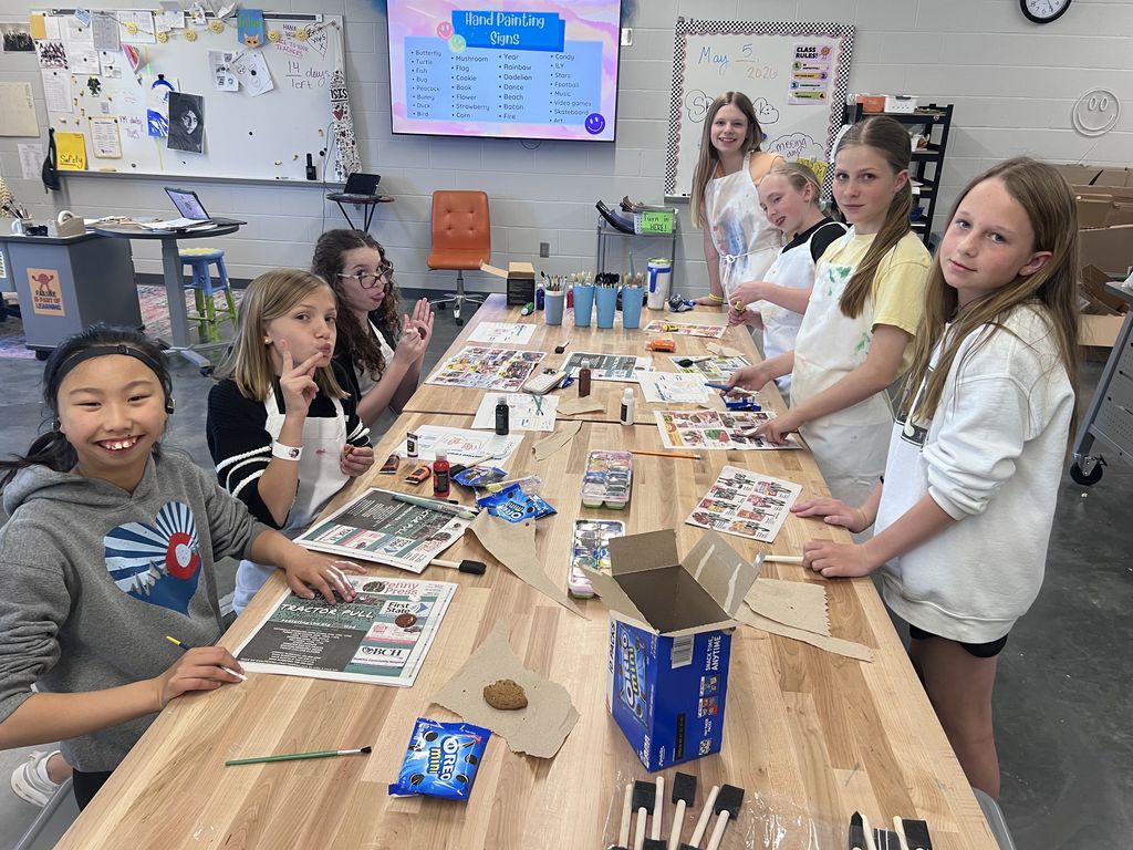 A group of kids painting at a long table. 