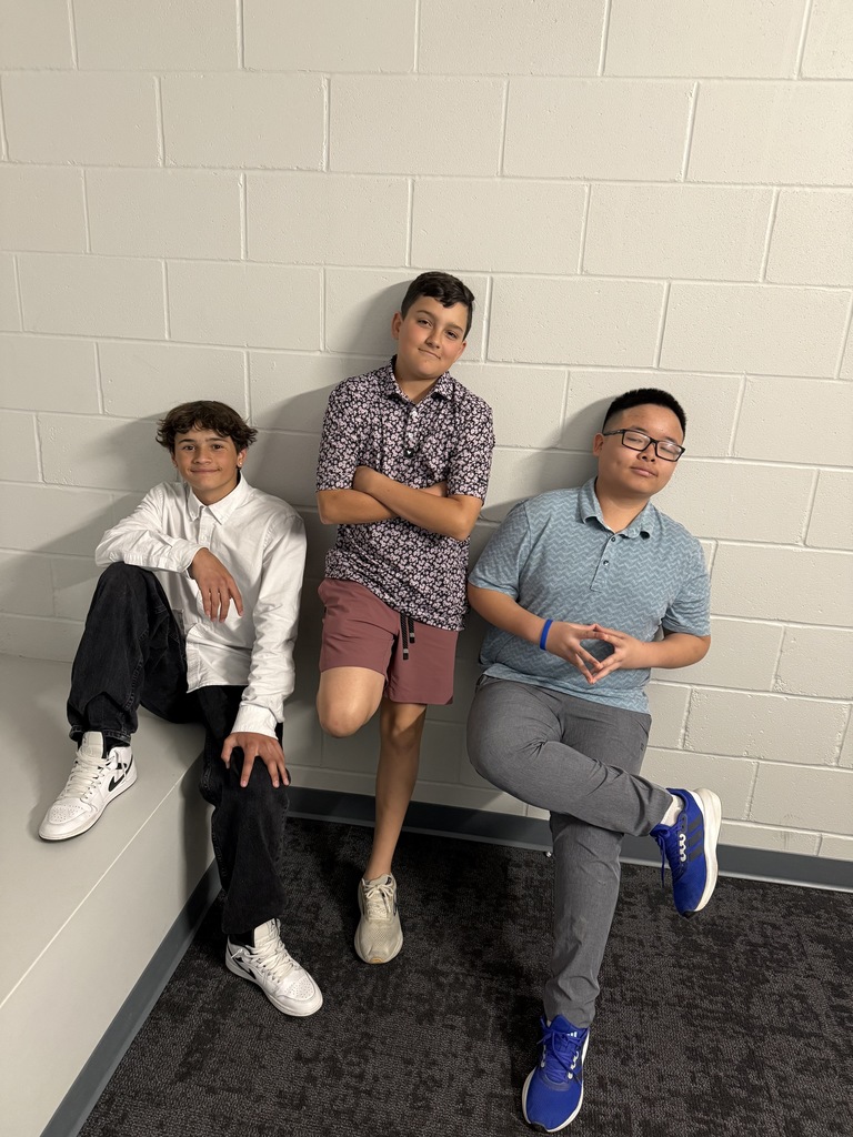 Three male students pose in the hallway for dress to impress day. 