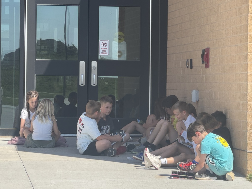 students reading outside in the outdoor classroom