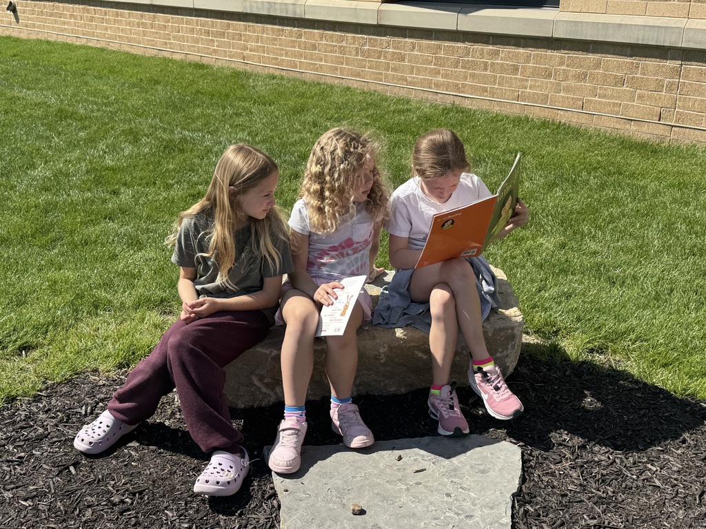 students reading outside in the outdoor classroom