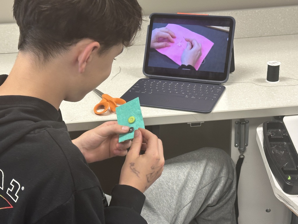 Photo of a male student sewing buttons.