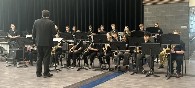 Photo of band director Mr. Cooley directing a group of band students for their performance.