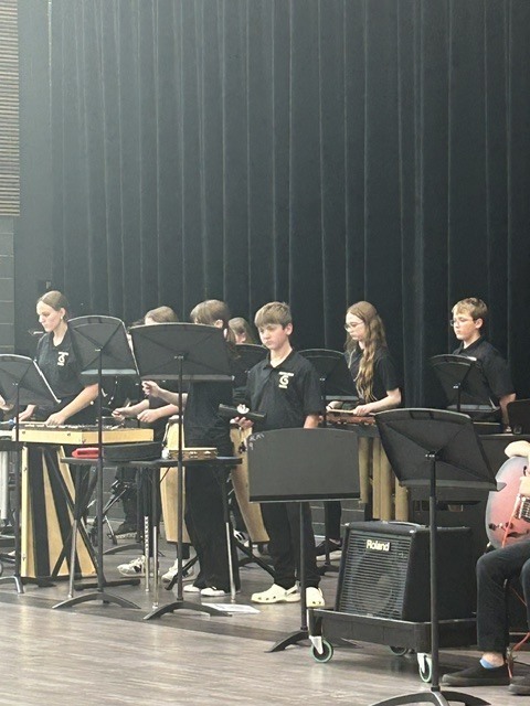 Photo of percussionists looking at music and playing their various instruments.