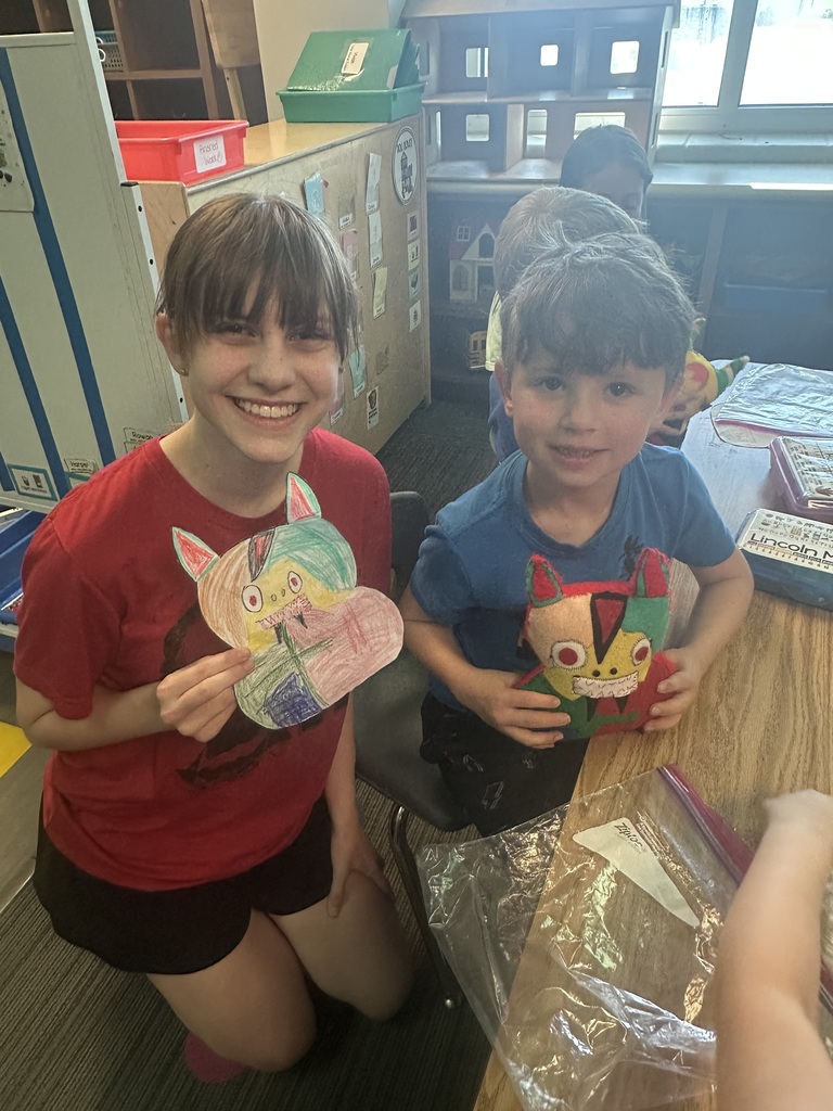 Photo of an 8th grader posing with a kindergartener the 8th grader is holding the design and the kindergartener is holding the matching monster.