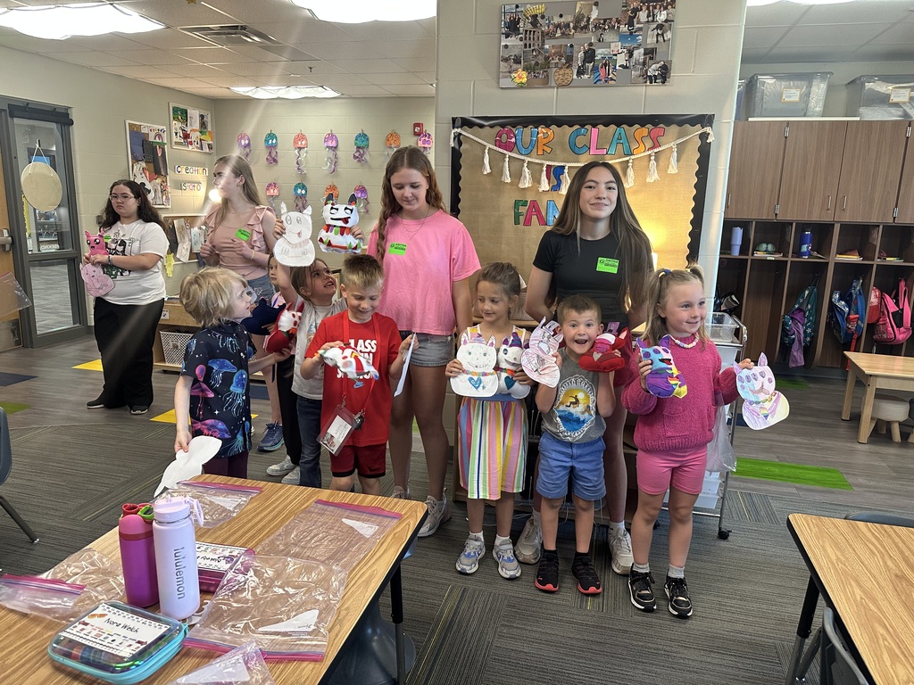 Photo of two 8th graders posing with multiple kindergarteners and their monsters.