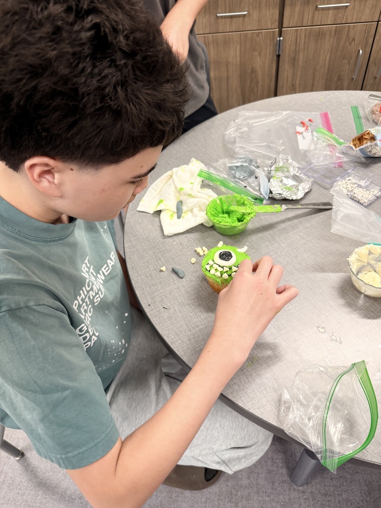 A student frosts a cupcake. 