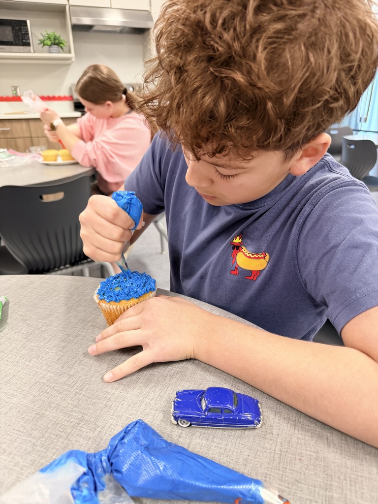 A student frosts a cupcake. 