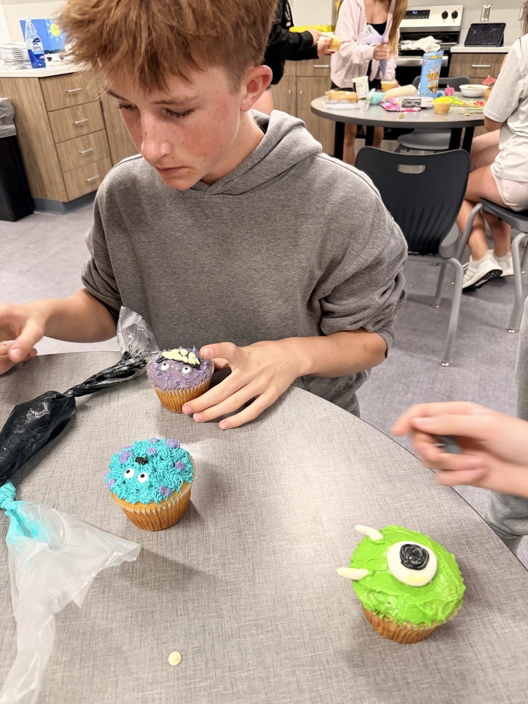 A student frosts a cupcake. 
