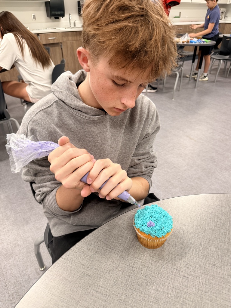 A student frosts a cupcake. 