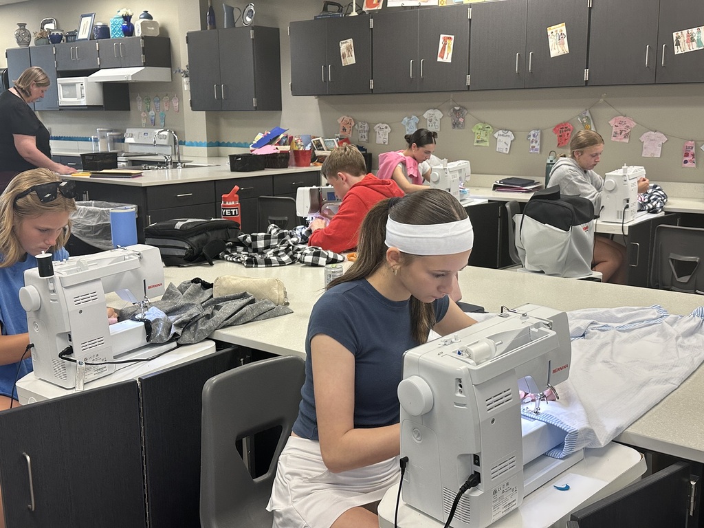 Photo of students sitting at sewing machines working on their pajama pants.