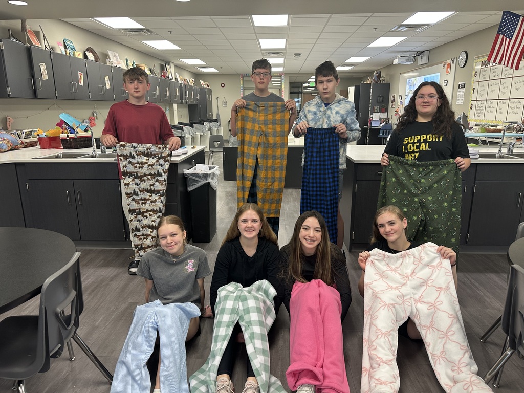 Photo of 8th grade students lined up in two rows holding their pajama pants.