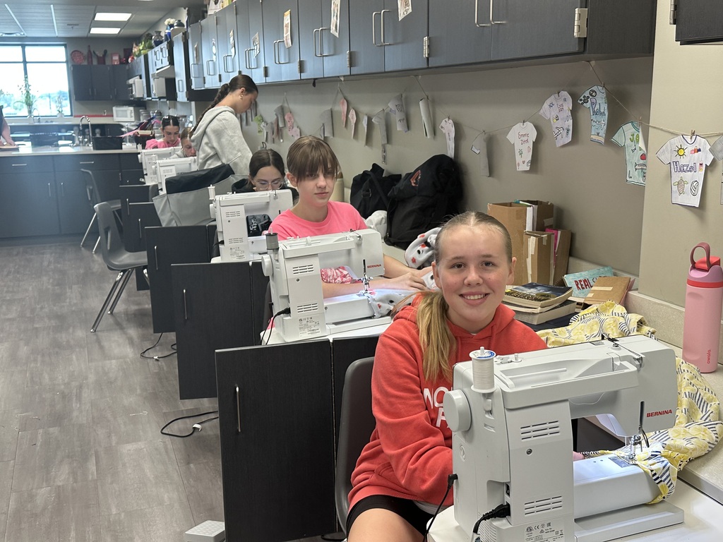 Photo of students sitting at sewing machines working on their pajama pants.