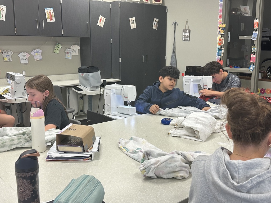 Photo of students sitting at sewing machines working on their pajama pants.