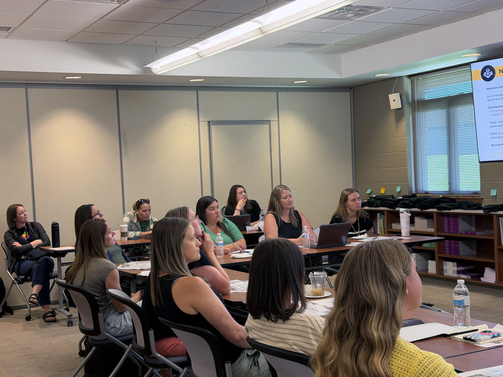 Tables of new hires and current staff members at tables during orientation to help out with laptops and benefits.