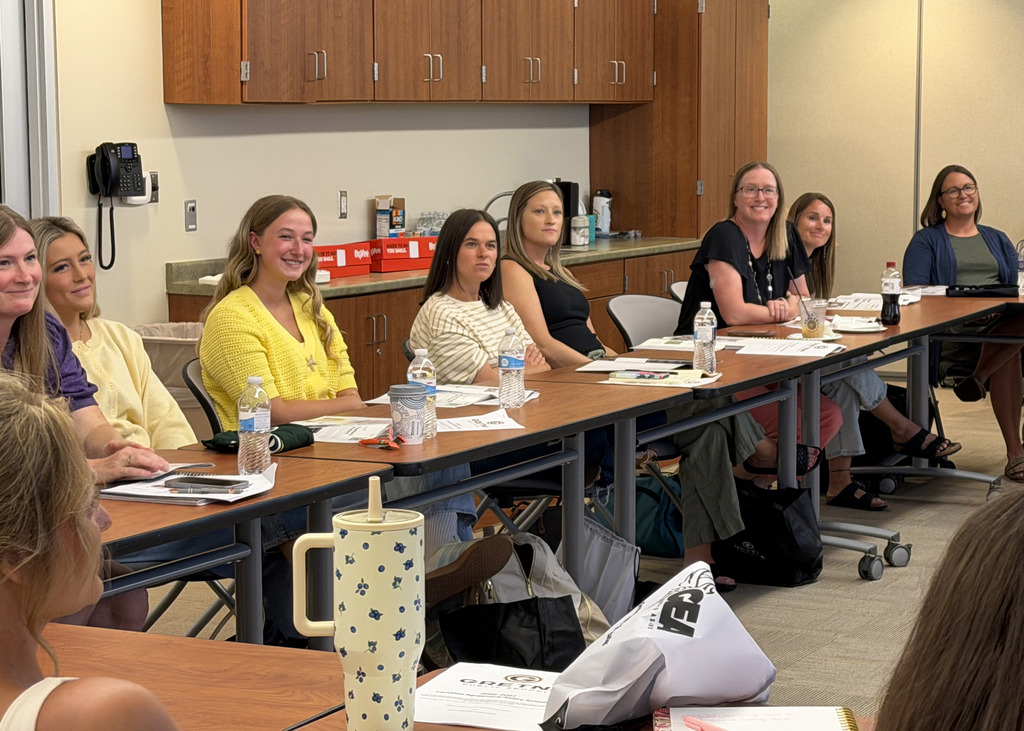 A group of smiling new staff members looking to the front of the room at the presenter