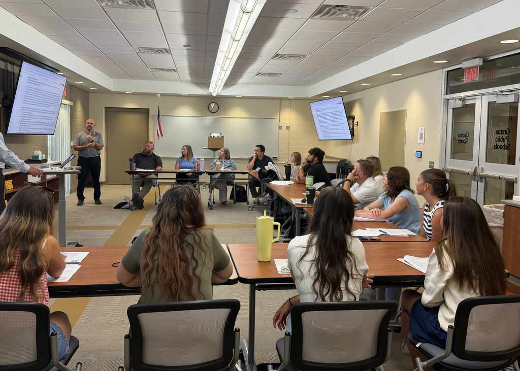 New staff members looking to the front of the room as the presenter discusses with them the upcoming training sessions