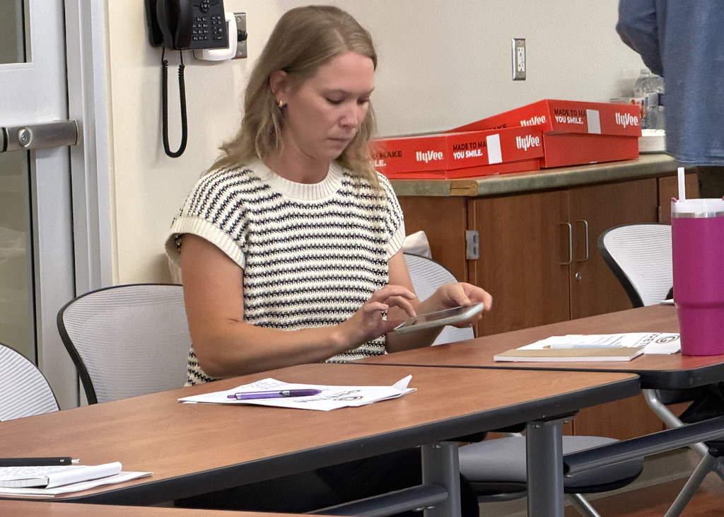 New staff member with papers on desk in front of them working on their phone to get set up with the GPS app.