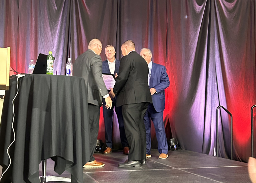 Superintendent Travis Lightle on stage receiving the HumanEx Exemplar Award for Education.