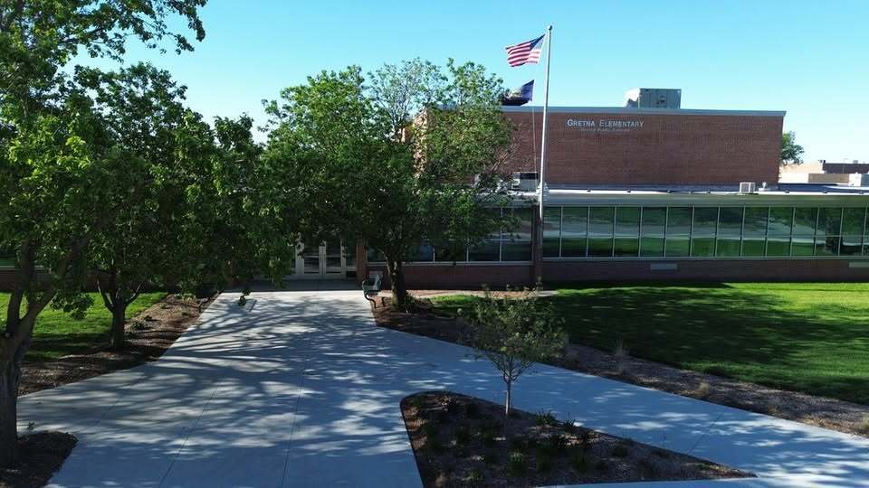 Photo of a school with green trees and grass showing