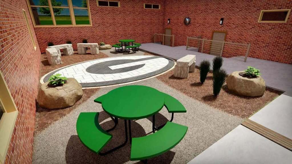 Outdoor classroom featuring a large G on the ground along with rocks and green tables.
