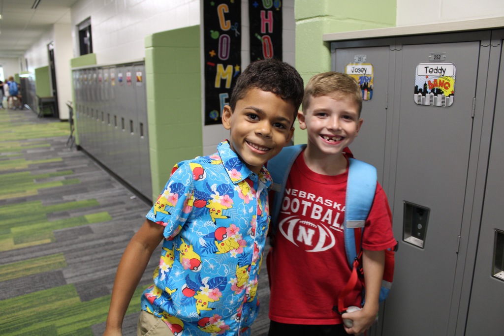 Two second grade boys stand with arms around shoulders smiling.