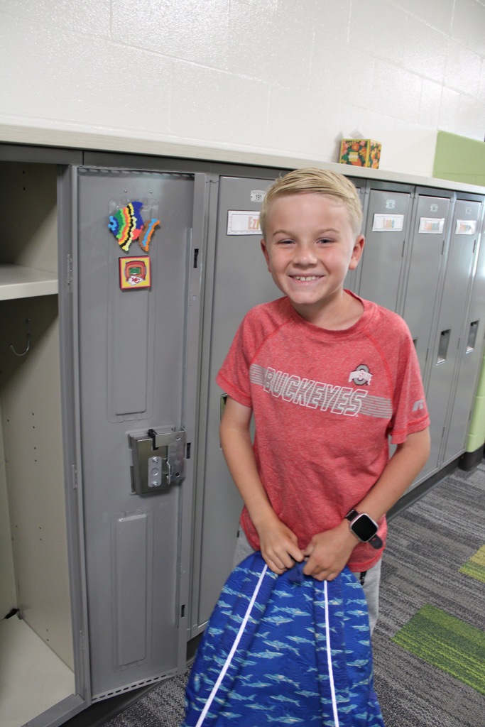 A third grade boy gets his locker ready for the first day.