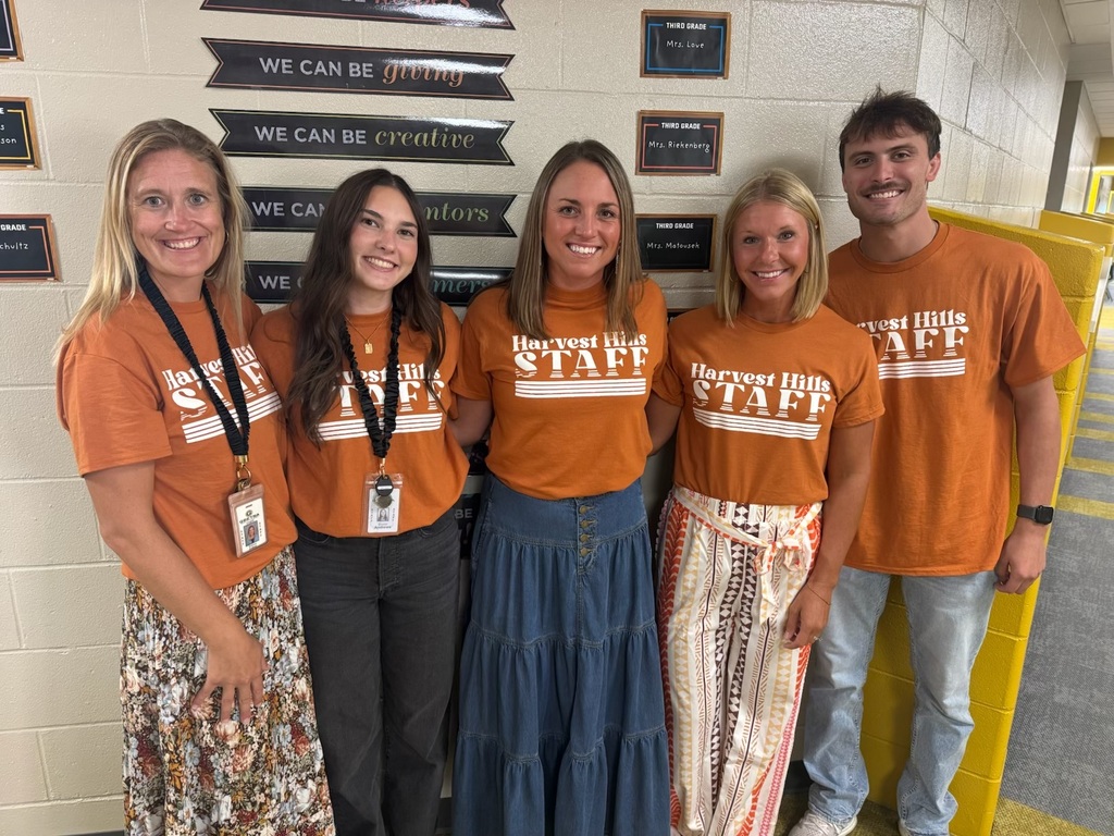 teachers smiling in matching shirts in the hallway
