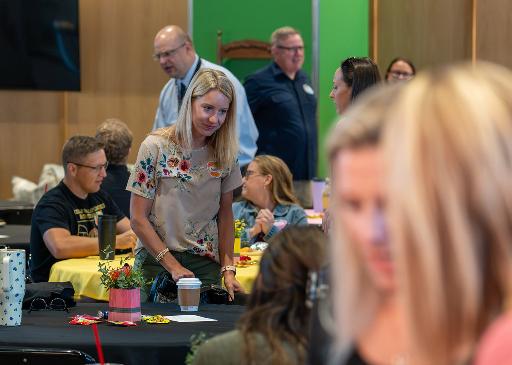 a group of new staff members gathered together eating breakfast and talking at tables