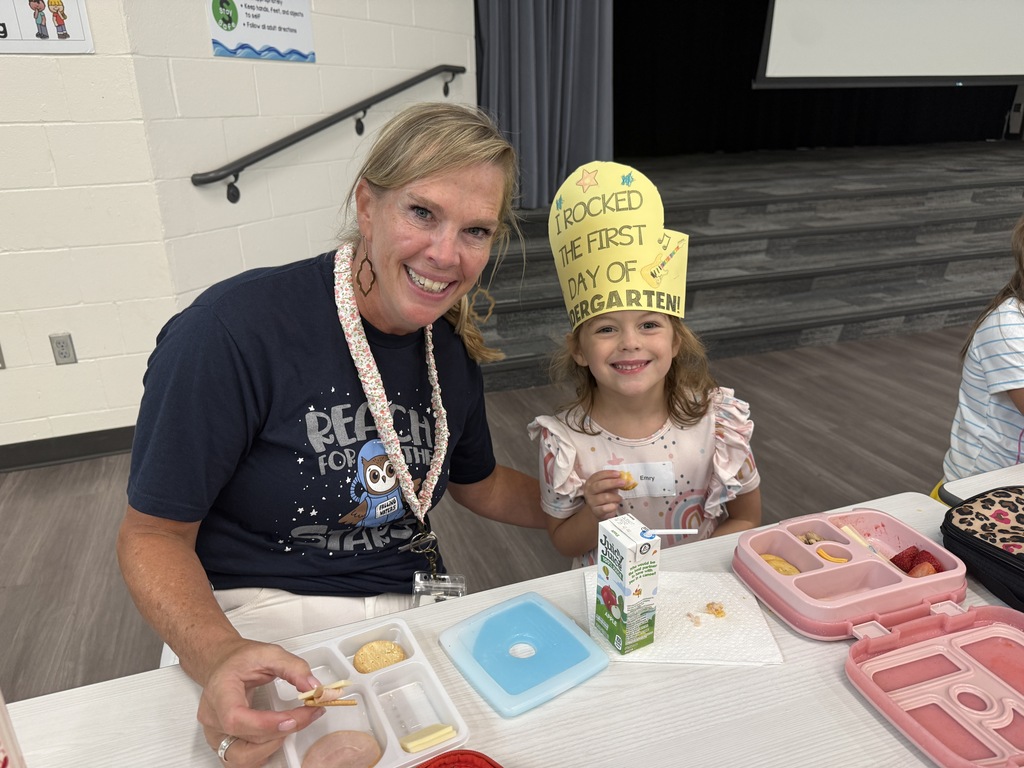 Mrs. Simmons eats lunch with a kindergarten girl wearing her "I rocked the first day of Kindergarten hat."